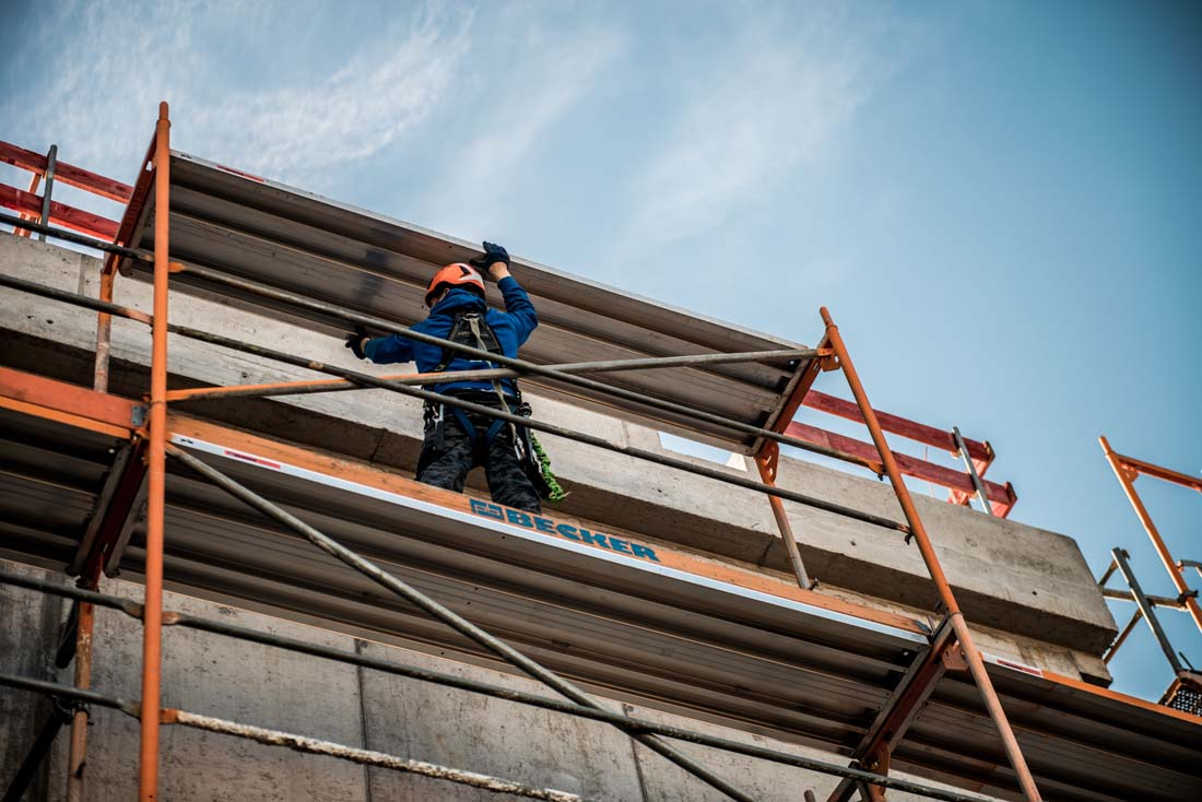 Worker in safety gear stands on scaffolding at construction
