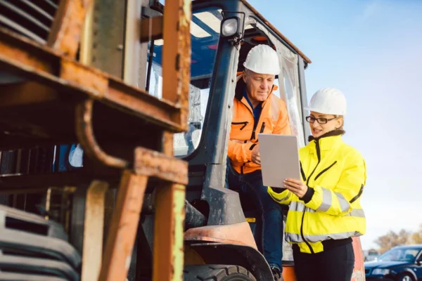 Construction workers in safety gear reviewing tablet onsite