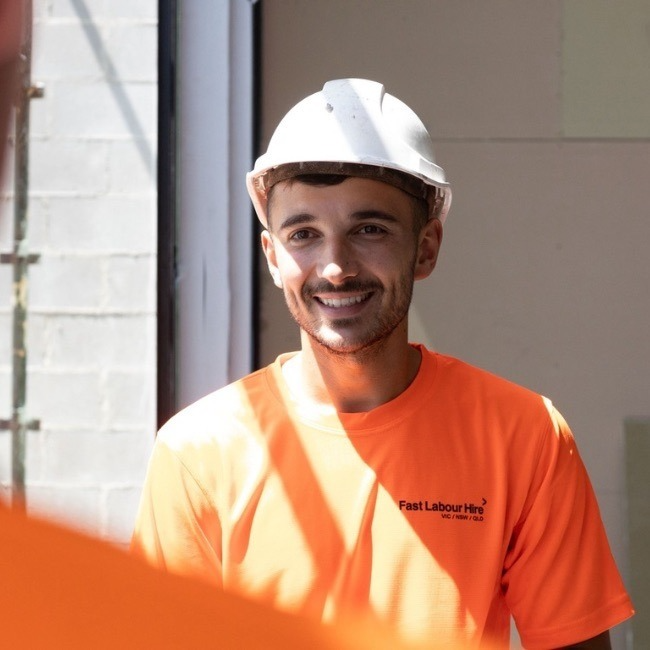 1-M-1 | Fast Labour Hire Construction worker smiles in white hard hat and orange shirt